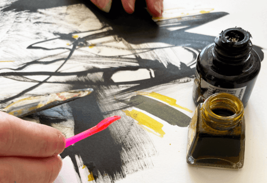 Hands exploring freeform painting techniques using black ink in an online art class