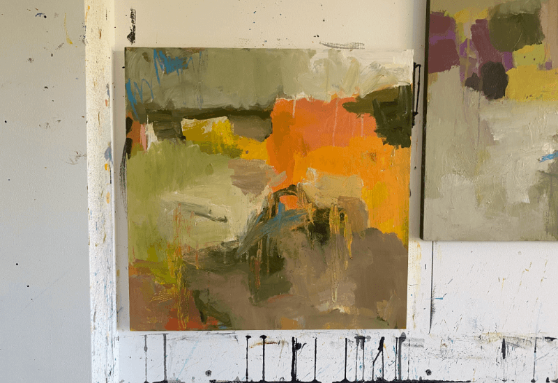 Abstract landscape painting in progress featuring bold, earthy tones of orange, green, and ochre, with expressive brushstrokes and visible texture.